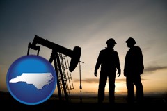 north-carolina map icon and an oil well and two oil workers at dusk