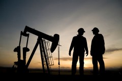 an oil well and two oil workers at dusk